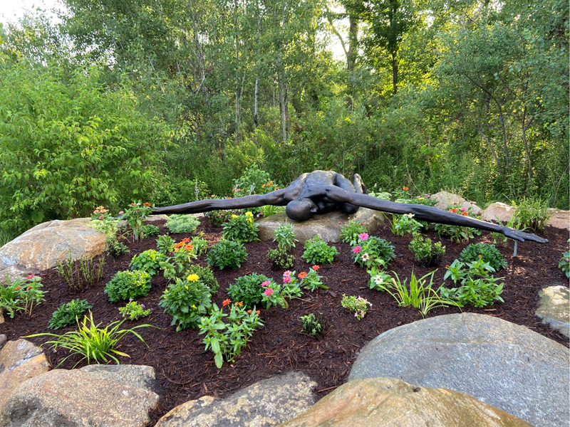 Sculpture surrounded by flowers and natural landscaping