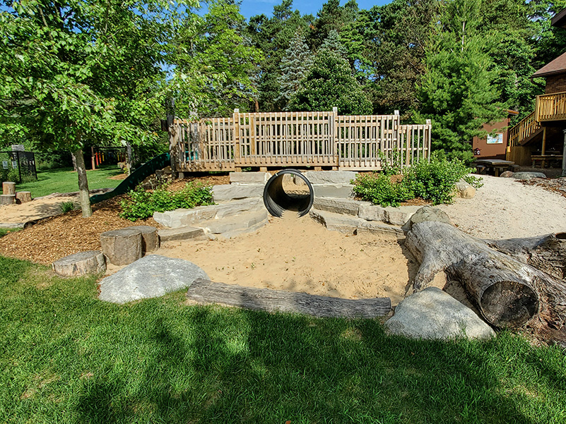 Natural play area with bridge and sandbox